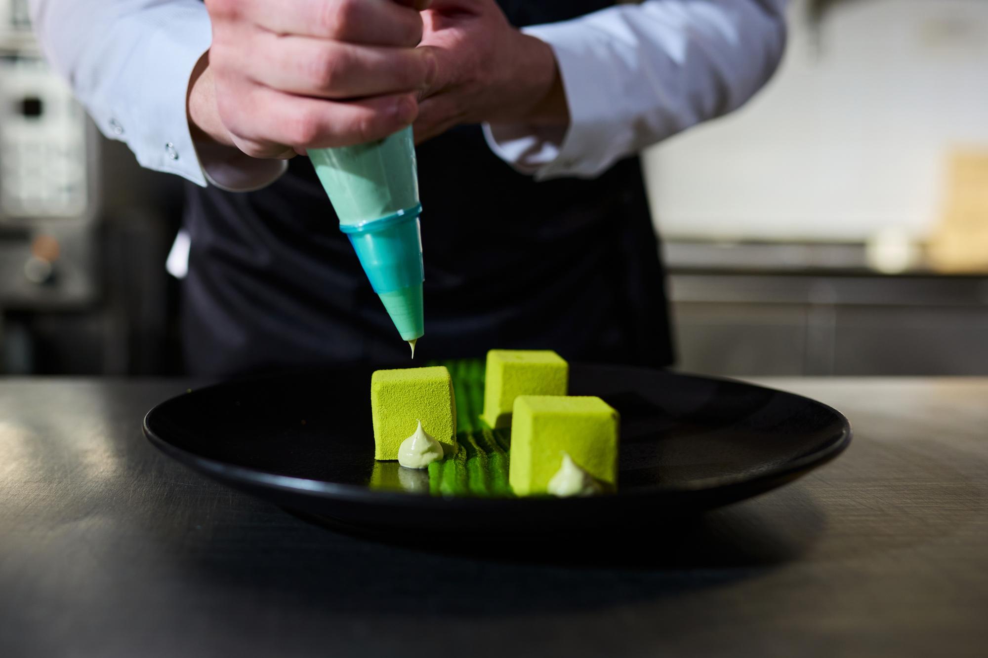 Chef preparing a plated dish with modern garnish